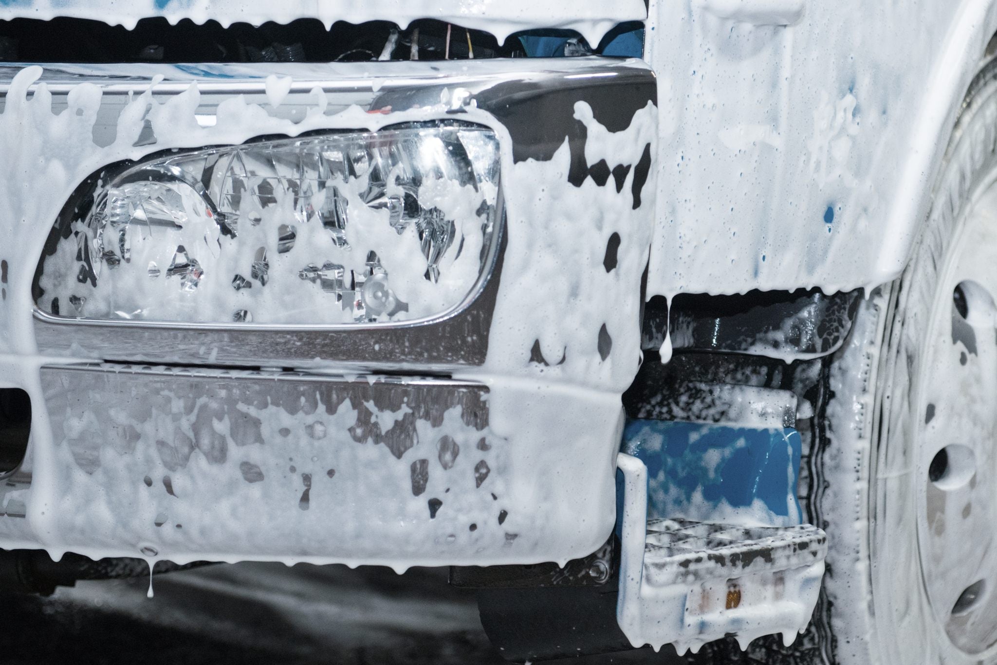Closeup on headlight of fleet vehicle being washed with fleet wash chemicals